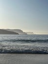 Vertical shot of foamy waves crashing the shore under the blue sky, cool for background