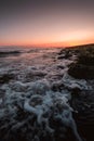 Vertical shot of foamy waves of the sea coming to the shore with the amazing sunset Royalty Free Stock Photo