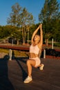 Vertical shot of focused young woman in activewear warming up training do lunges exercise by water in city park on