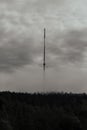 Vertical shot of a foggy mountain with a metallic thin tower on its peak