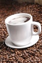 Vertical shot of fresh espresso cup on background of coffee beans Royalty Free Stock Photo
