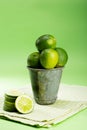 Vertical shot of fresh limes in a meal container on green background with sliced limes on the side Royalty Free Stock Photo