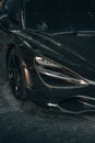 Vertical shot of the front and the headlight of black McLaren luxury sports car