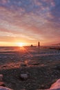 Vertical shot of a frozen beach with a small lighthouse under the cloudy sunset Royalty Free Stock Photo