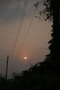 Vertical shot of a full moon in a cloudy sky with silhouettes of trees and power electric lines Royalty Free Stock Photo