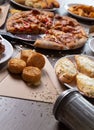 Vertical shot of a full restaurant table with pizza, garlic bread, and cheese bites Royalty Free Stock Photo