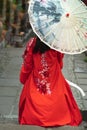 Vertical shot of a geisha walking in the street with a red dress and umbrella - shot from back Royalty Free Stock Photo