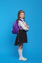 Vertical shot of girl wearing backpack and school uniform, holding books Royalty Free Stock Photo