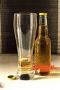 Vertical shot of a glass and a bottle of cold beer on a white table Royalty Free Stock Photo