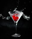 Vertical shot of a glass of cocktail with a strawberry and splashing water on black background Royalty Free Stock Photo