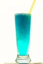 Vertical shot of a glass of delicious blue lagoon drink with a straw isolated on a white background