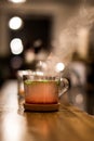 Vertical shot of a glass of herbal tea with a wooden saucer on a blurred background
