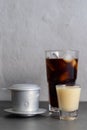Vertical shot of a glass of iced coffee, condensed milk and a Vietnamese coffee filter
