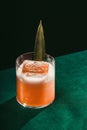 Vertical shot of glass of pineapple trainwreck cocktail on green surface