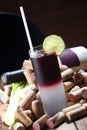 Vertical shot of a glass of a vodka cranberry cocktail drink surrounded with wine corks