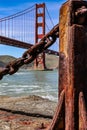 A vertical shot of the Golden Gate Bridge behind a rusty fence at Fort Point Royalty Free Stock Photo