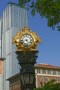 Vertical shot of a golden watch behind a skyscraper