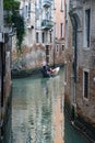 Vertical shot of a gondolier navigating on the canal in Venice surrounded by humble buildings