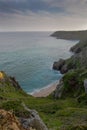 Vertical shot of grassy cliffs and the ocean in the background on Pedn Vounder Beach, Cornwall