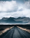 Vertical shot of a gravelroad leading towards the scenic mountains in the majestic Iceland Royalty Free Stock Photo