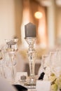 Vertical shot of gray candle on transparent silver glass candlestick on wedding reception table