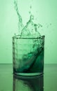 Vertical shot of a green cocktail splash on a green background Royalty Free Stock Photo