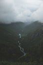 Vertical shot of green mountains and a river under the beautiful white clouds Royalty Free Stock Photo