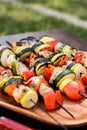 Vertical shot of grilled vegetable and chicken kabobs on a wooden plate