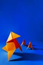 Vertical shot of a group of orange origami figures on blue background