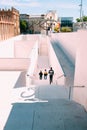 Vertical shot of a group of people going down the white stairs near beautiful buildings Royalty Free Stock Photo