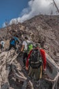 Vertical shot of a group of young hikers and a landscape of a burned forest around the Volcanic cone in the danger zone in the