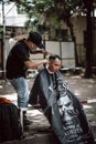 Vertical shot of the hairdresser cutting a men's hair in Ho Chi Minh, Vietnam