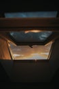 Vertical shot of a half-opened window allowing light from a sunset to creep in Royalty Free Stock Photo