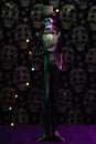 Vertical shot of a Halloween figurine against a grungy skull wall with purple lights background