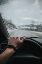 Vertical shot of a hand holding on the black steering wheel while driving in the car Royalty Free Stock Photo