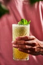 Vertical shot of a hand holding a glass of cocktail with mint on the top of it Royalty Free Stock Photo