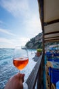 Vertical shot of a hand holding a glass with drink at Positano Amalfi coast in Italy Royalty Free Stock Photo