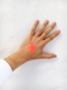 Vertical shot of a hand on a white background with a cross made of orange bandaids