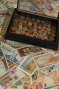 Vertical shot of a handful of numismatic collection banknotes and a wooden box with coins from various countries of the world in a