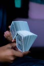 Vertical shot of hands doing a trick with a set of poker cards with a purple background. Royalty Free Stock Photo