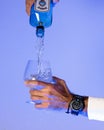 Vertical shot of the hands pouring Bombay gin into a glass with the Casio G-SHOCK