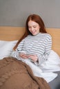 Vertical shot of happy young woman enjoy shopping online with credit card and mobile phone lying in bed at home. Royalty Free Stock Photo