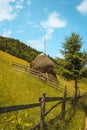 Vertical shot of a haybale located in a grass field on the slope of a hill