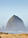 Vertical shot of the Haystack Rock in the morning fog at Cannon Beach, Oregon Royalty Free Stock Photo