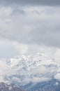 Vertical shot of a high rocky mountain covered with snow under a cloudy sky Royalty Free Stock Photo