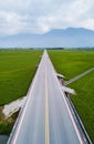 Vertical shot of a highway in the middle of green fields Royalty Free Stock Photo