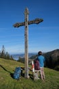 Vertical shot of a hiker standing next to a wooden cross looking at the mountains in Switzerland Royalty Free Stock Photo