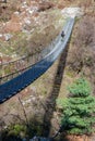 A vertical shot of a hiker walking on the suspended footbridge in Tal village, Dharapani, Nepal Royalty Free Stock Photo