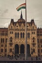 Vertical shot of the historic Parliament Building and a flag on a pole in Budapest, Hungary