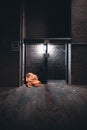 Vertical shot of a homeless person sleeping under an orange blanket in front of a building Royalty Free Stock Photo